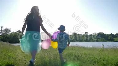 快乐的孩子们手拿彩色气球在绿色的草坪上漫步